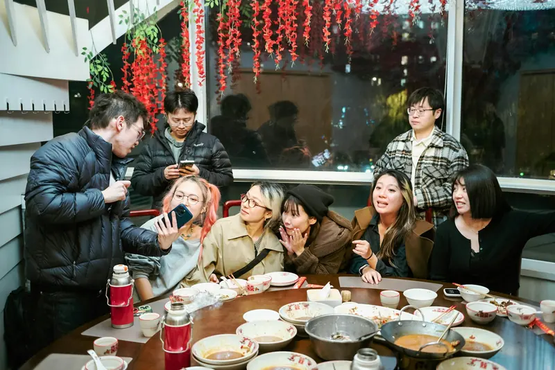 Grupo de amigos adultos comiendo juntos alrededor de una mesa redonda