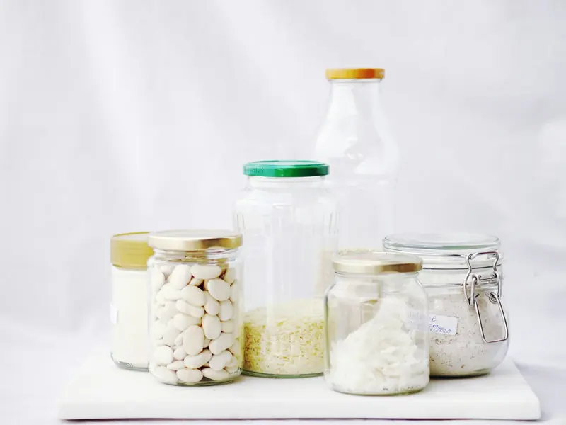 Tarros de cristal con alubias blancas, arroz y otros cereales sobre fondo claro