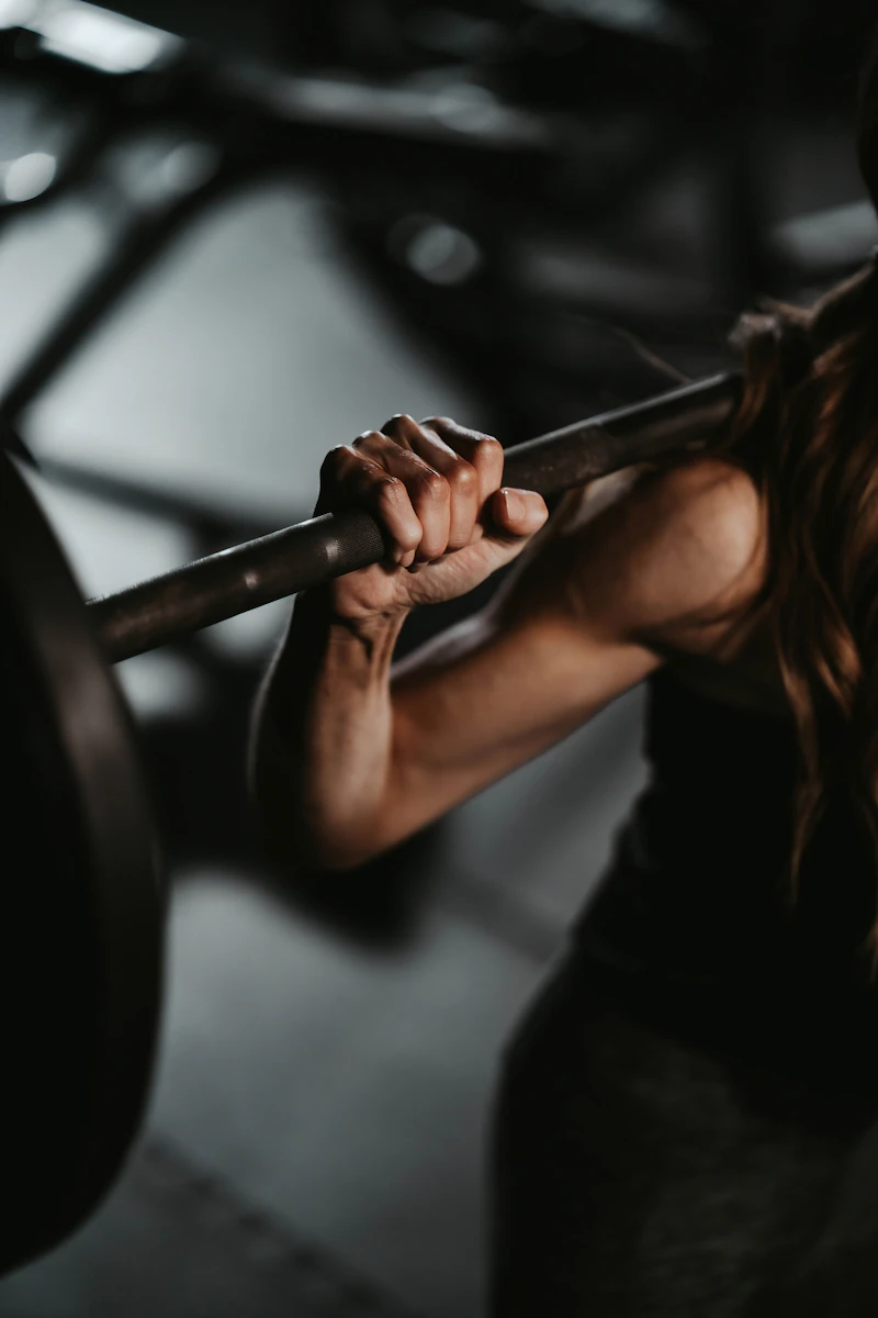 Mujer agarrando una barra con discos en el gimnasio
