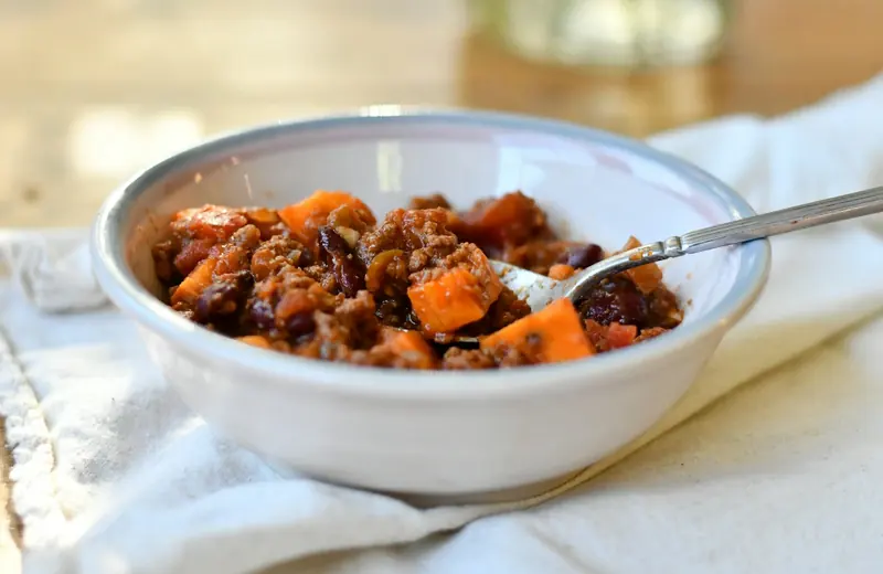 Bowl of homemade legume stew with sweet potato and a spoon