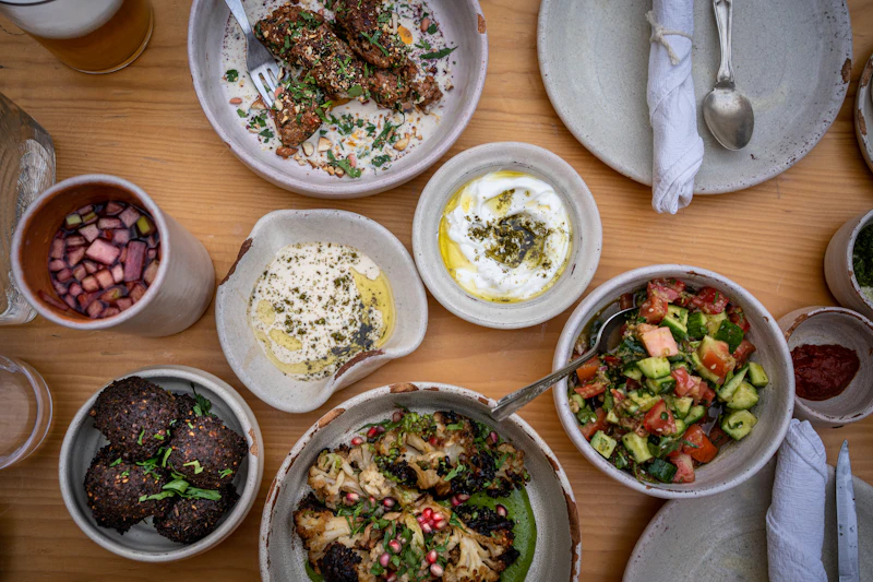 Table with plates and bowls of Mediterranean food seen from above