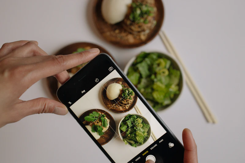 Persona fotografiando con el móvil una mesa de comida