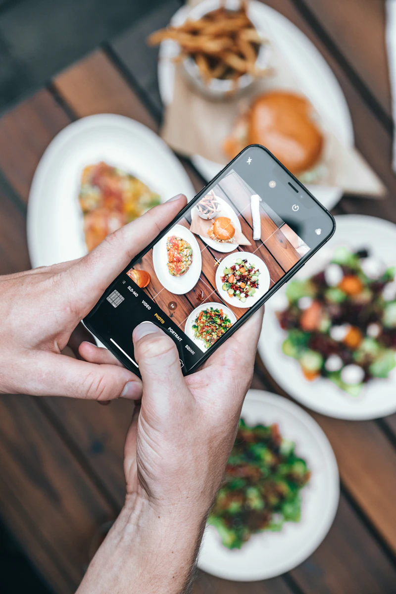 Manos sujetando un móvil para fotografiar un plato de comida