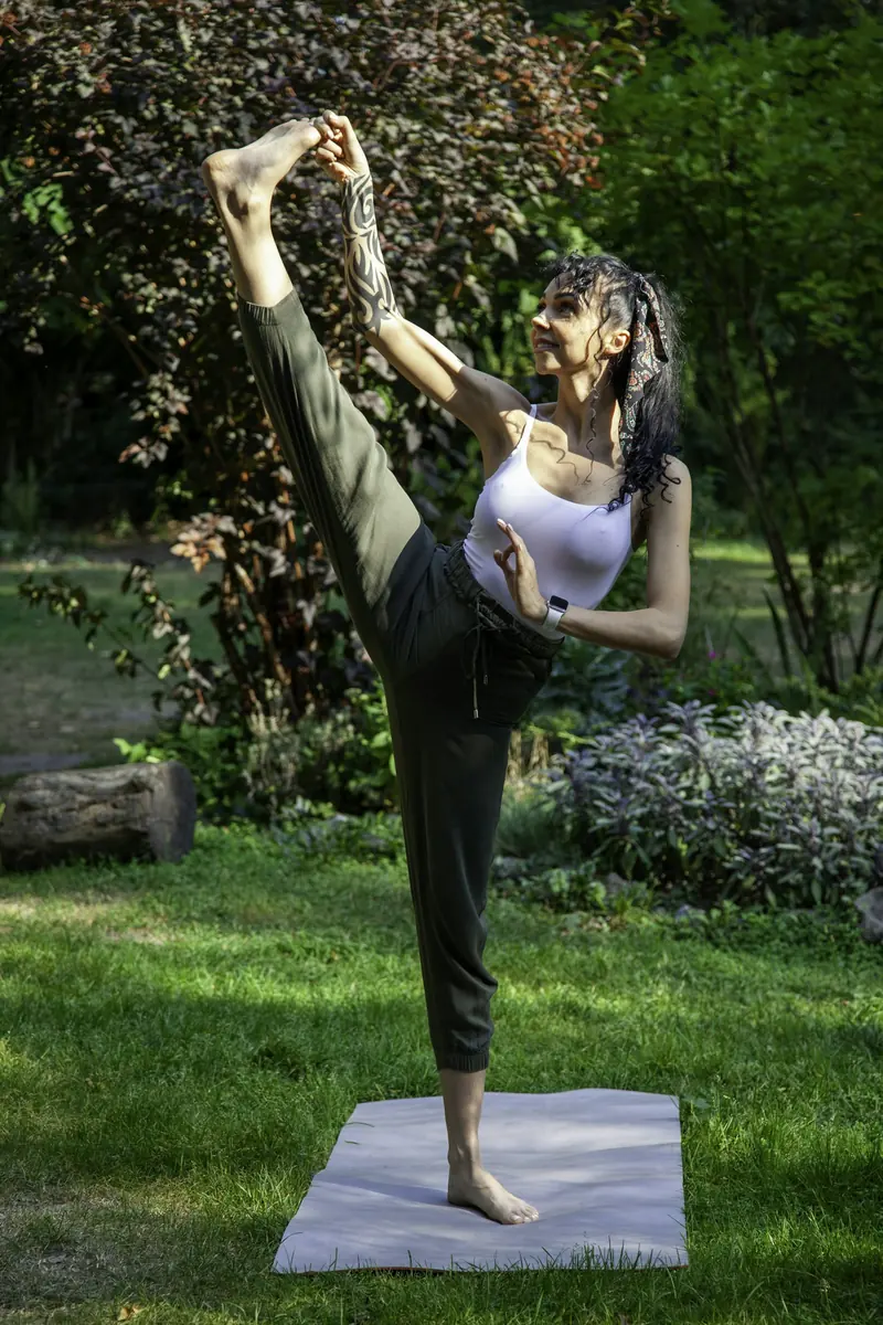 Emakume bat parke batean yoga-jarrera bat egiten koltxoneta baten gainean